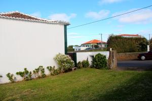 a white house with a yard next to a building at Casa do Sr. Alberto in Praia da Vitória