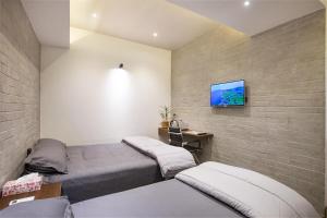 錫爾赫特的住宿－Rahma’s B&B，一间卧室设有两张床,砖墙上配有电视