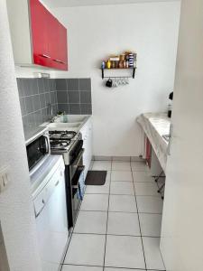 uma pequena cozinha com fogão e armários brancos em Appartement t2 au chartrons em Bordéus