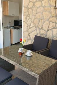 a table with two cups and a vase with flowers on it at Apartments and rooms by the sea Metajna, Pag - 6496 in Metajna