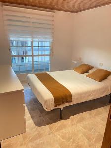 - une chambre avec un grand lit et une fenêtre dans l'établissement Apartamento vacacional en O Grove, à O Grove