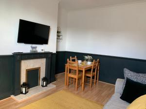 een woonkamer met een tafel en een tv boven een open haard bij Faraday - Central location Ideal for contractors and visiting Newcastle Free Wifi Free Parking in Gateshead
