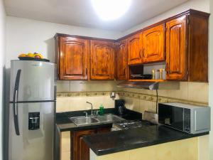 una cucina con mobili in legno e un frigorifero in acciaio inossidabile di Ocean View Apart. In Down town a San Felipe de Puerto Plata