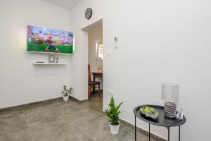 ein Wohnzimmer mit einem TV an der Wand und einem Tisch in der Unterkunft Lovely apartment M&K in peaceful area - Zadar in Zadar