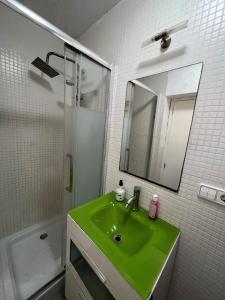 La salle de bains est pourvue d'un lavabo vert et d'une douche. dans l'établissement Malvarrosa habitación cómoda y sencilla cerca de la playa, à Valence