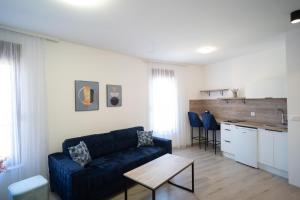 a living room with a blue couch and a kitchen at Apartments and rooms SMILE in Mostar