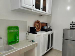 eine Küche mit weißen Schränken und einem grünen Tablett auf der Theke in der Unterkunft Appartement calme et confortable in Al Ghar