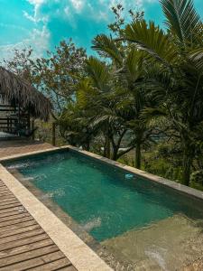 a swimming pool with a wooden deck and palm trees at All Natural Glamping in Copacabana