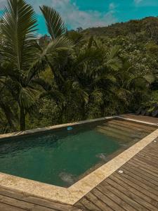 een zwembad met palmbomen en een houten terras bij All Natural Glamping in Copacabana
