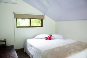 a white bedroom with a bed with a flower on it at Tinny House in La Fortuna #1 in Fortuna