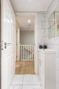 a white bathroom with a sink and a door at Comfy Friendly Stay in London