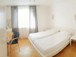 a white bed in a room with a desk and a window at Sonniges 2-Zimmer-Gartenapartment in Bietigheim-Bissingen