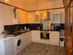 a kitchen with white cabinets and a washer at Rodsley - 2 bedroom 1st floor flat Free Parking WiFi and Netflix in Gateshead