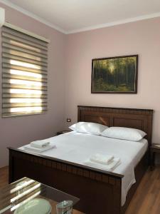 a bedroom with a large bed with white sheets and a window at Villa Garden in Berat