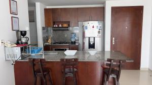 a kitchen with a counter with stools and a refrigerator at Apartamento Cartagena in Cartagena de Indias