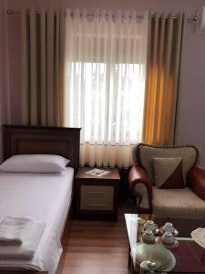 a bedroom with a bed and a chair and a table at Villa Garden in Berat