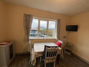 um pequeno quarto com uma mesa e uma janela em Shalom bungalow Falcarragh Mountain View em Falcarragh