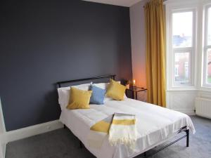 Heaton-Beautiful 3 Double Bedrooms Sleeps 6 Free Parking and Wifi في نيوكاسل أبون تاين: غرفة نوم بسرير مع مخدات صفراء و زرقاء