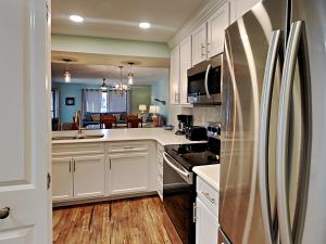 a kitchen with white cabinets and a stainless steel refrigerator at Edgewater Villa 2406 in Panama City Beach