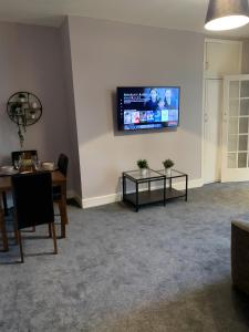 a living room with a table and a tv on the wall at Heaton-Beautiful 3 Double Bedrooms Sleeps 6 Free Parking and Wifi in Newcastle upon Tyne