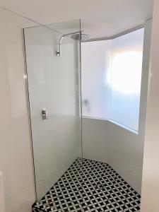 a glass shower with a black and white tile floor at Resort Queen Studio at Alex Beach Resort in Alexandra Headland