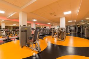 une salle de sport avec plusieurs rangées de tapis de course dans l'établissement Leonardo Royal Hotel Den Haag Promenade, à La Haye