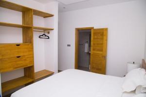 a bedroom with a white bed and wooden shelves at Habia Residence in Grand-Popo +12 photos