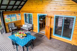 a wooden cabin with a table and chairs on a deck at Raintree Gardens - 1 Acre, Ocean Views, Steps from beach in Matei