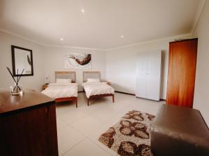 a bedroom with two beds and a couch in it at Sunset Villa in Langebaan