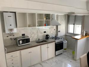 a kitchen with white cabinets and a sink and a microwave at Cabo Corrientes - Mar del Plata - Preguntar antes de reservar in Mar del Plata