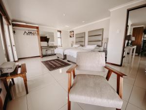 a large white bedroom with a bed and a chair at Sunset Cottage in Langebaan