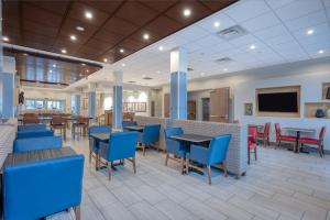 uma área de jantar com cadeiras e mesas azuis numa cafetaria em Holiday Inn Express & Suites St. Louis - Chesterfield, an IHG Hotel em Chesterfield