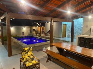 a large room with a pool with a table and a bench at Casa Ametista in Pirenópolis