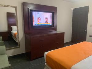 Habitación con TV, cama y espejo. en HOTEL DORADO DIAMANTE, en Mexicali