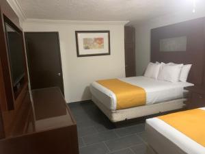 a hotel room with two beds and a television at Hotel Dorado Baja in Mexicali