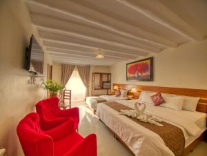 a hotel room with two beds and two red chairs at Sol Ollantay Exclusive Hotel in Ollantaytambo