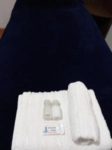 a white towel with two bottles on a bed at hostel comunidad Ushuaia in Ushuaia