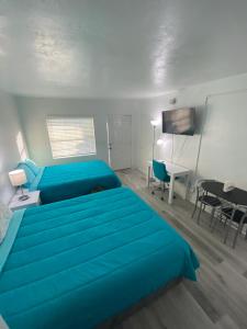 a bedroom with two blue beds and a desk at Uptown Inn & Suites in St. Petersburg