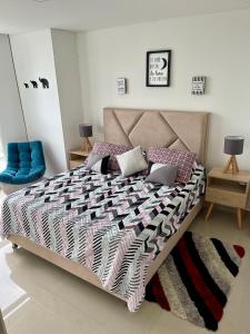 a bedroom with a large bed with a blue chair at Moderno y cómodo apartamento en Puerta del Sol in Bucaramanga