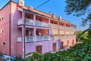 una casa rosa con balconi e alberi bianchi di Rooms with a parking space Veli Losinj, Losinj - 21045 a Veli Lošinj (Lussingrande)
