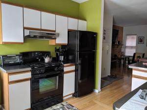 eine Küche mit einem schwarzen Kühlschrank und weißen Schränken in der Unterkunft The Whitney in Buffalo