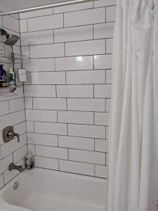 ein Badezimmer mit einer weißen Badewanne und einem Duschvorhang in der Unterkunft The Whitney in Buffalo
