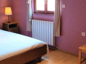 1 dormitorio con paredes moradas, 1 cama y ventana en Semi-detached house, Hinsbourg, en Hinsbourg