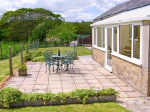 a patio with a table and chairs in a yard at 1 Cowdea Farm in Marshwood