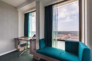 Habitación con ventana, sofá azul y escritorio. en Leonardo Hotel Amsterdam Rembrandtpark en Ámsterdam