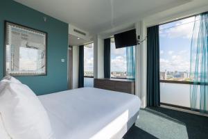a bedroom with a large white bed and windows at Leonardo Hotel Amsterdam Rembrandtpark in Amsterdam