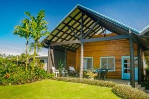 a wooden house with a patio and a lawn at Raintree Gardens - 1 Acre, Ocean Views, Steps from beach in Matei