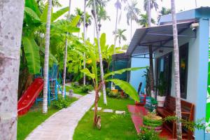 una casa con palmeras y un parque infantil en suri mũi né homestay en Phan Thiet