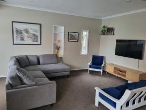 a living room with a couch and a flat screen tv at Redwoods Character Cottage & Studio in Rotorua
