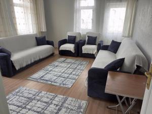 uma sala de estar com sofás, uma mesa e janelas em Acan Apart günlük kiralık ev daire Ürgüp em Mustafapaşa